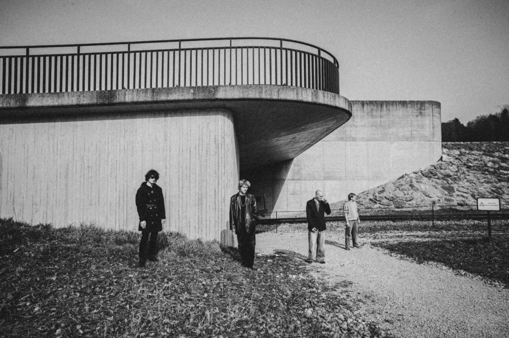 Schwarz-Weiss-Bandfoto: vier Musiker vor einer geschwungenen Betonbrücke, darunter Thierry Bill