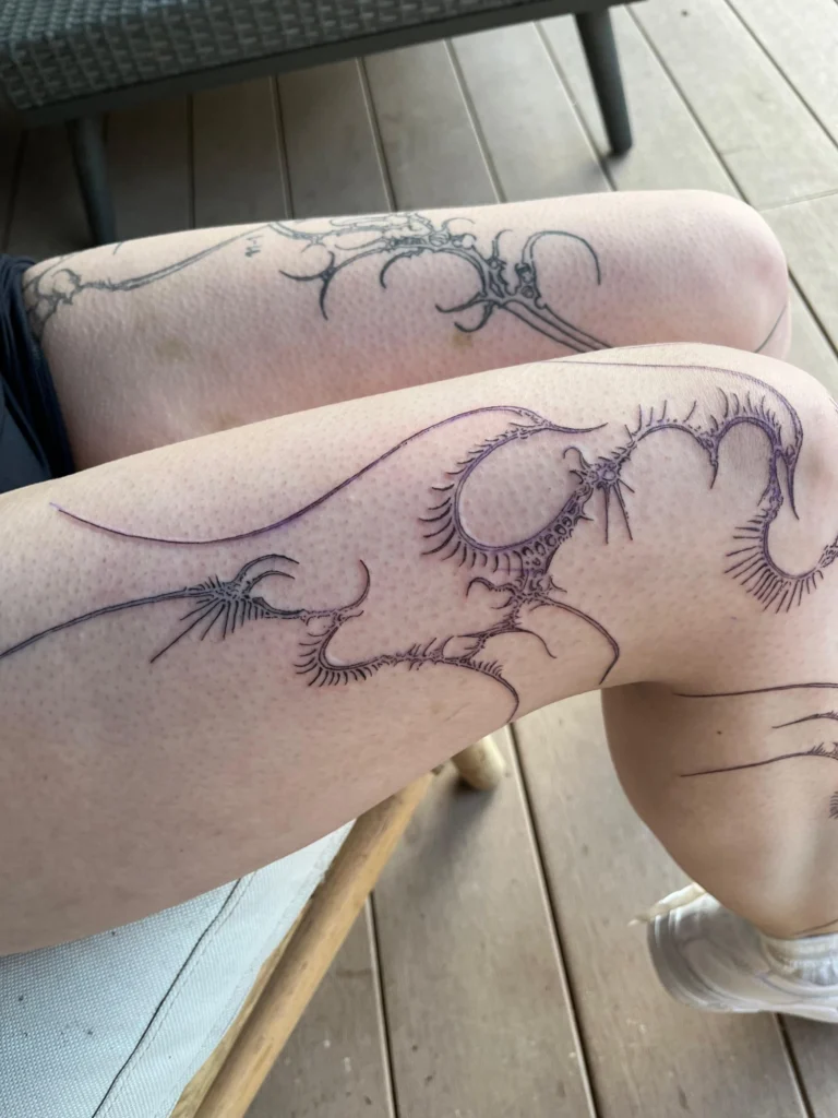 Feines Linework-Tattoo von Thierry Bill: organische, verästelte Ornamente über Oberschenkel und Knie