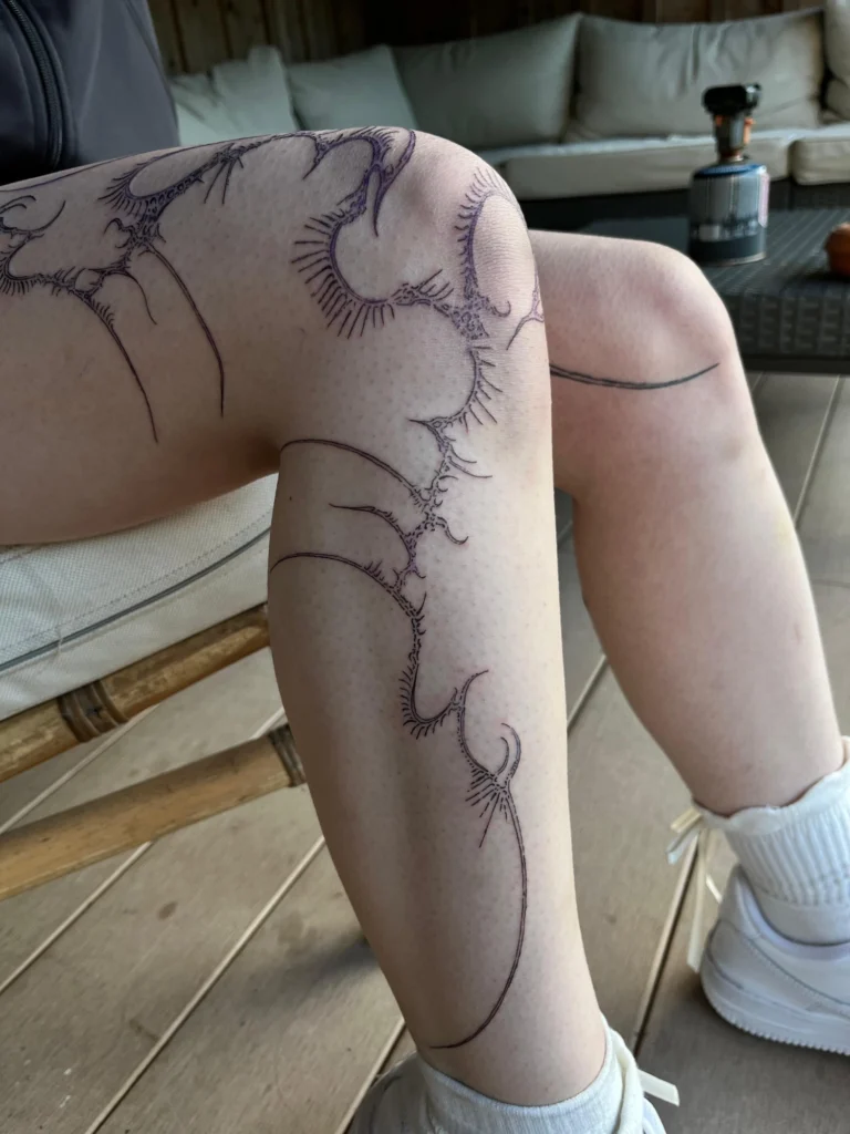 Linework-Tattoo von Thierry Bill: organische Ornamente ziehen sich vom Knie über das ganze Schienbein