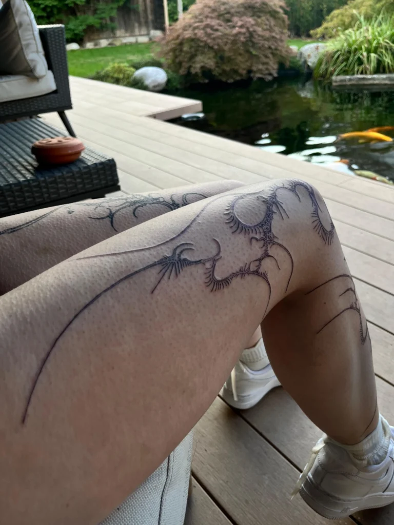 Linework-Tattoo von Thierry Bill: filigrane, verästelte Ornamente mit feinen Strahlen über Knie und Oberschenkel