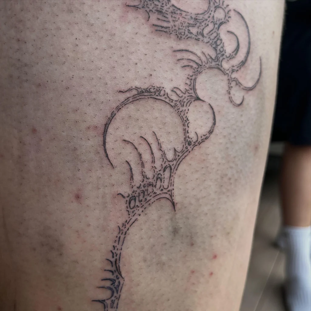 Nahaufnahme eines verheilten Linework-Tattoos von Thierry Bill auf dem Oberschenkel: Kreise und verästelte Linien