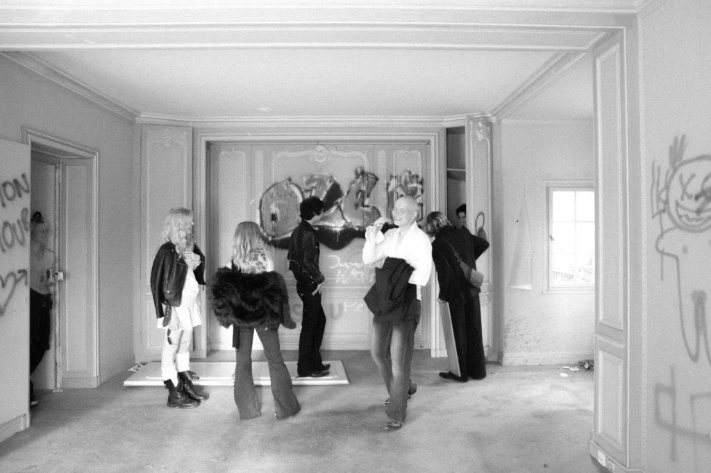 Schwarz-Weiss-Foto: Thierry Bill lachend mit Freundinnen und Freunden in einem leerstehenden Altbau mit Graffiti